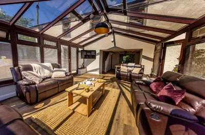 a living room with leather couches and a coffee table at The Farmhouse, Sebergham, spacious family or group accommodation in a rural setting close to Caldbeck in Sebergham