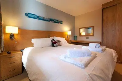 a large white bed with a teddy bear sitting on it at Keswick Bridge 5,within walking distance of Keswick town centre, strictly no pets in Keswick