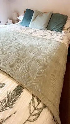 a bed with a comforter on top of it at Farm stay caravan on working farm in Dacre