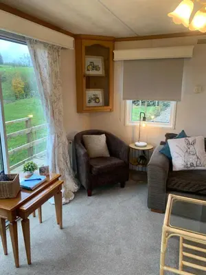 a living room with a couch and a chair and a window at Farm stay caravan on working farm in Dacre