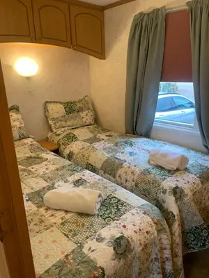 a small room with two beds and a window at Farm stay caravan on working farm in Dacre