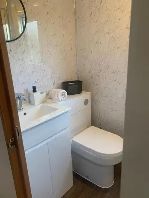 a bathroom with a white toilet and a sink at Farm stay caravan on working farm in Dacre