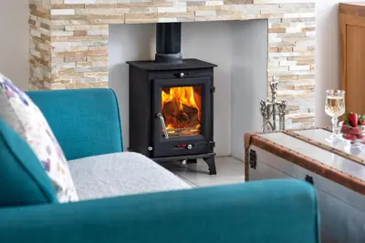 a fireplace in a living room with two chairs and a stove at Cottage - Sleeps 3 hot tub & pet friendly in Carlisle