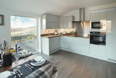 a kitchen with white cabinets and a table and a window at Corriedow in Thornhill