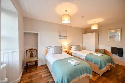 a bedroom with two beds and a chair in it at 3 bedroom townhouse right on the harbour in Isle of Whithorn