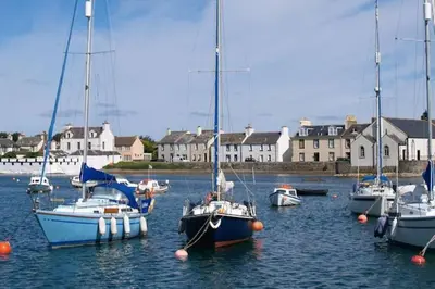 a group of boats are docked in the water at 3 bedroom townhouse right on the harbour in Isle of Whithorn