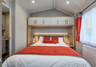 a bedroom with a large bed with red pillows at Elite Holiday Caravan in Bassenthwaite