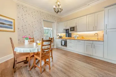 a kitchen with white cabinets and a table and chairs at Redwood Rise Apartment Keswick at The Lairbeck in Keswick