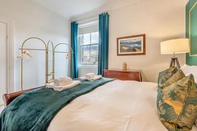 a bedroom with a large bed with blue curtains at Cameron Fell Apartment Keswick at The Lairbeck in Keswick