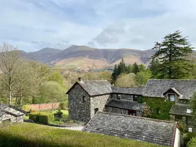 an old stone house with mountains in the background at Cameron Fell Apartment Keswick at The Lairbeck in Keswick