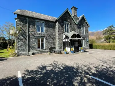 an old stone building with a parking lot in front of it at The Capsule Room at The Lairbeck in Keswick in Keswick
