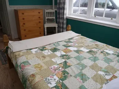 a bedroom with a bed with a quilt on it at The Drovers Cabin in Kirkcudbright