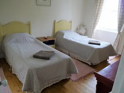 a bedroom with two beds and a wooden floor at The Drovers Cabin in Kirkcudbright