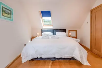 a bedroom with a large white bed with a window at Kinnen Cottage in Creetown