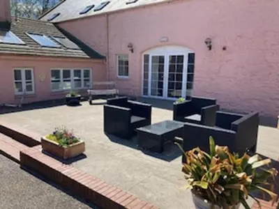 a patio with black furniture in front of a pink building at The Wickerman Granary in Kirkcudbright