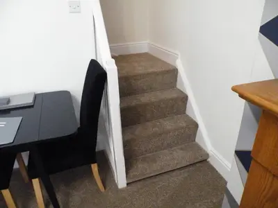 a staircase with a table and a chair next to a stair case at Family Home Near City Centre - New KING bed! in Carlisle