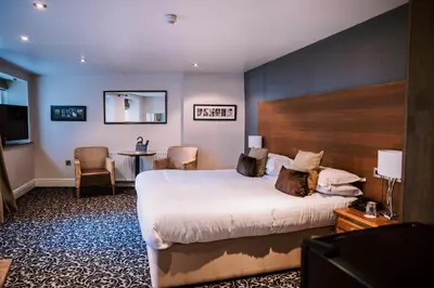 a hotel room with a bed and a table and chairs at Allerdale Court Hotel in Cockermouth