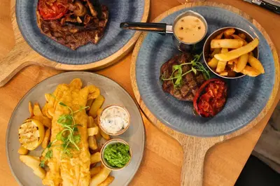 a table with three plates of food and french fries at Allerdale Court Hotel in Cockermouth