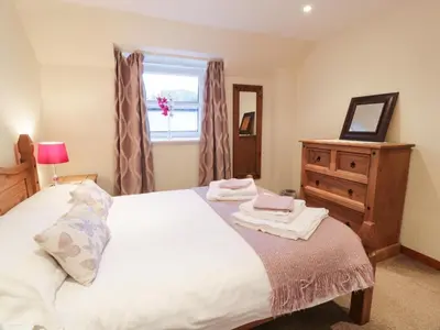 a bedroom with a bed and a dresser and a window at Barley Cottage in Newton Stewart
