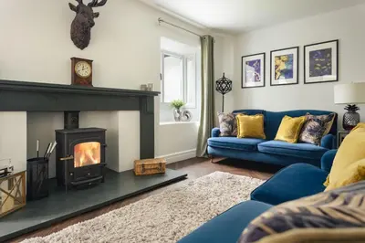 a living room with a blue couch and a fireplace at Bellfoot Rural Retreat and Hot Tub in Grasmere