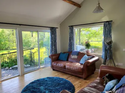 a living room with a leather couch and sliding glass doors at Lingmoor Cottage in Chapel Stile