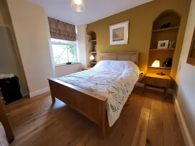 a bedroom with a bed with a wooden floor and a window at Lingmoor Cottage in Chapel Stile