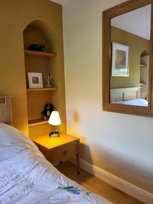 a bedroom with a mirror and a bed and a lamp at Lingmoor Cottage in Chapel Stile