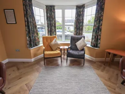a living room with two chairs and a table and windows at Limhus House in Keswick
