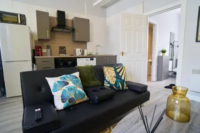 a black couch in a living room with a kitchen at 1 BDR Apt By Caledonia Luxe Stays Short Lets & Serviced Accommodation Lanark in Douglas