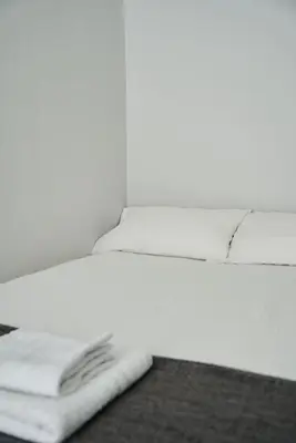 a white bed with a pile of towels on it at 1 BDR House By Caledonia Luxe Stays Short Lets & Serviced Accommodation Lanark in Douglas
