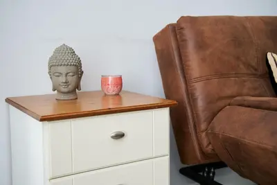 a side table with a statue on it next to a chair at 1 BDR House By Caledonia Luxe Stays Short Lets & Serviced Accommodation Lanark in Douglas