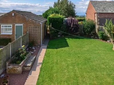 a garden with a lawn hose attached to a house at Rivendell in Burgh by Sands