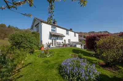 a large white house with flowers in the yard at 3 Bed in Elterwater oc-gl011 in Chapel Stile