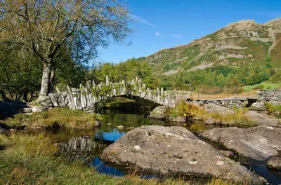 a stone bridge over a river with rocks and trees at 3 Bed in Little Langdale oc-gl102 in Little Langdale