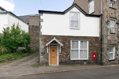 a brick house with a yellow door on a street at 2 Bed in Portinscale oc-gl129 in Portinscale