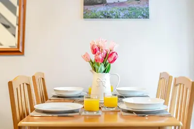 a table with plates and a vase of flowers and orange juice at 2 Bed in Grasmere oc-ld175 in Grasmere