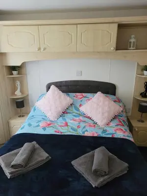 a bed with two pillows and towels on it at The Sunny Bunny Holiday Home in Ballantrae