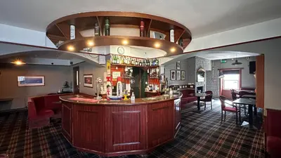 a bar in a pub with a bar counter at The Bruce Hotel in Newton Stewart