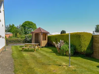 a garden with a bench and a gazebo at Rose Rigg Cottage in Kirklinton