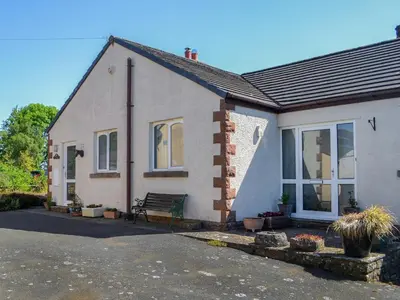 a white house with a bench in front of it at Rose Rigg Cottage in Kirklinton
