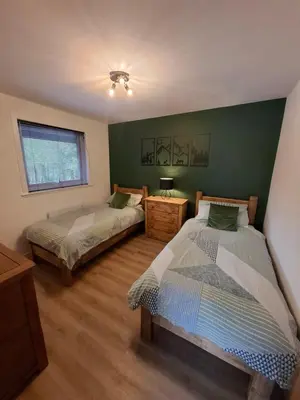 two beds in a room with green walls at Cairnyard Lodges - Woodrow in Beeswing
