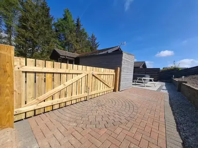 a wooden fence next to a brick patio at Cairnyard Lodges - Woodrow in Beeswing