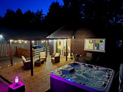 a hot tub on a deck at night at Cairnyard Lodges - Woodside in Beeswing