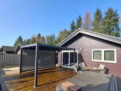 a house with a deck with a black roof at Cairnyard Lodges - Woodside in Beeswing