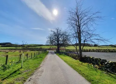 a dirt road next to a fence and a river at Strathken Cottage in Castle Douglas