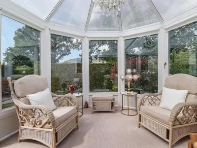 a conservatory with two chairs and a chandelier at Oaklea in Keswick