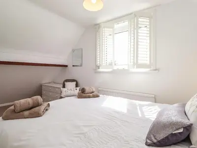 a bedroom with a large white bed with two stuffed animals on it at Oaklea in Keswick