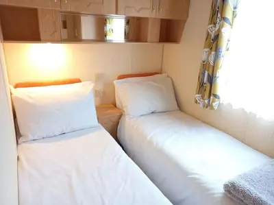 two beds in a small room with a window at Treetops in Lamplugh