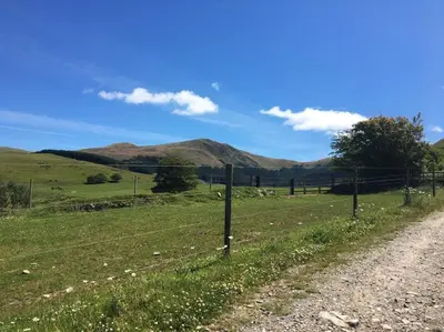 a fence on a field with mountains in the background at Treetops in Lamplugh