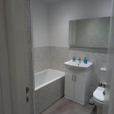 a bathroom with a tub and a sink and a toilet at J & S Apartments in Ayr